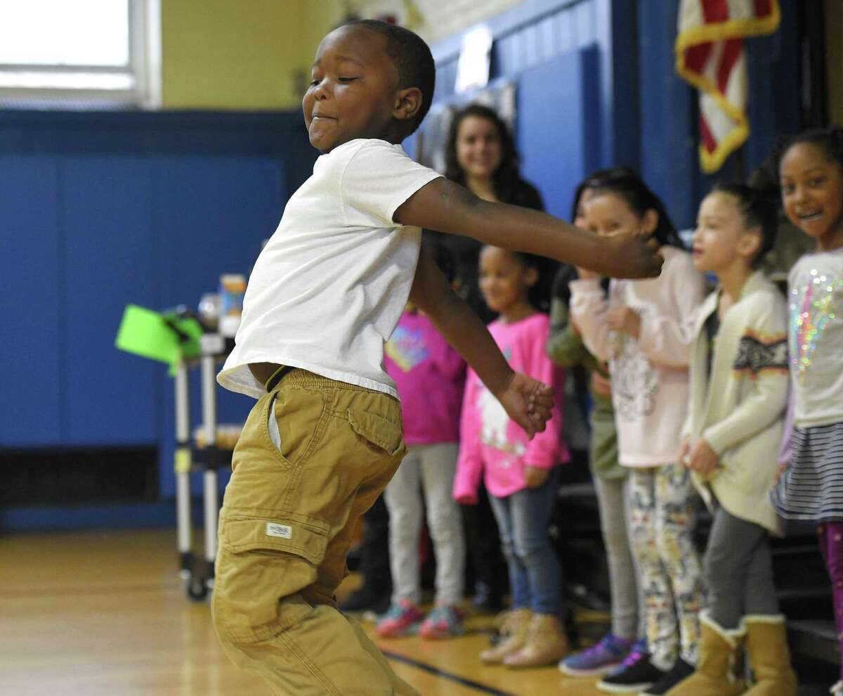 Kindergartner Shane Daniels dances for the "Move It, Move It" presentation during the Enrichment Clusters sharing assembly at Tracey School in December.