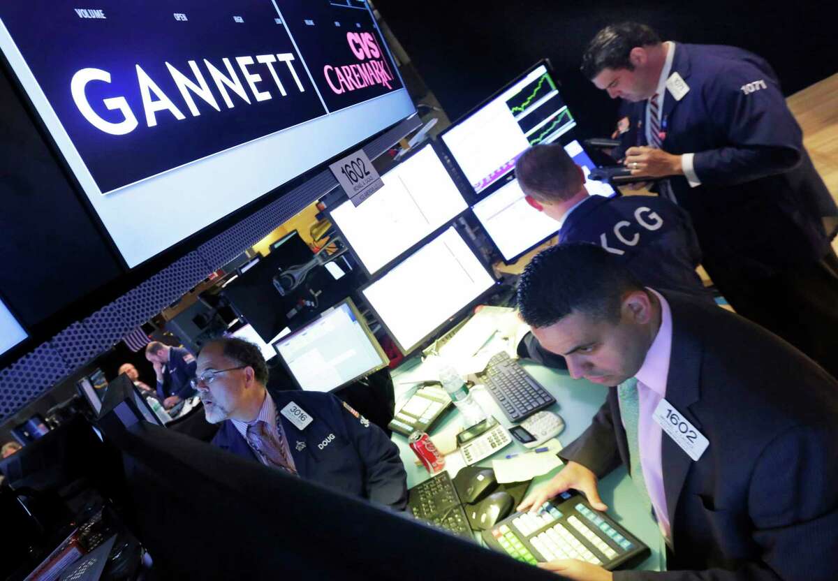 FILE - In this Aug. 5, 2014, file photo, specialist Michael Cacace, foreground right, works at the post that handles Gannett on the floor of the New York Stock Exchange. Gannett, publisher of USA Today, said Monday, Feb. 4, 2019, that its board has unanimously rejected a $1.36 billion buyout offer from a media group with a history of taking over struggling newspapers and slashing jobs. (AP Photo/Richard Drew, File)