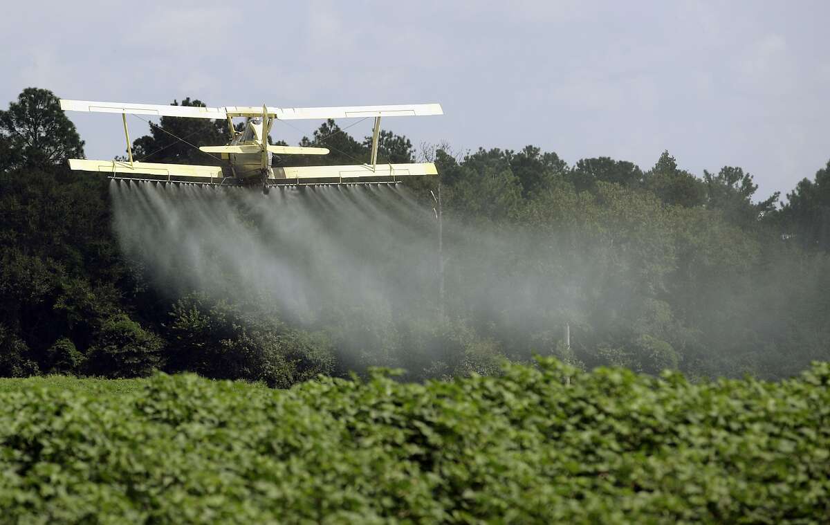 In this photo taken Aug. 4, 2009 file photo, a crop duster sprays a field of crops just outside Headland, Ala. Dow Chemical is pushing the Trump administration to scrap the findings of federal scientists who point to a family of widely used pesticides as harmful to about 1,800 critically threatened or endangered species. (AP Photo/Dave Martin, File)