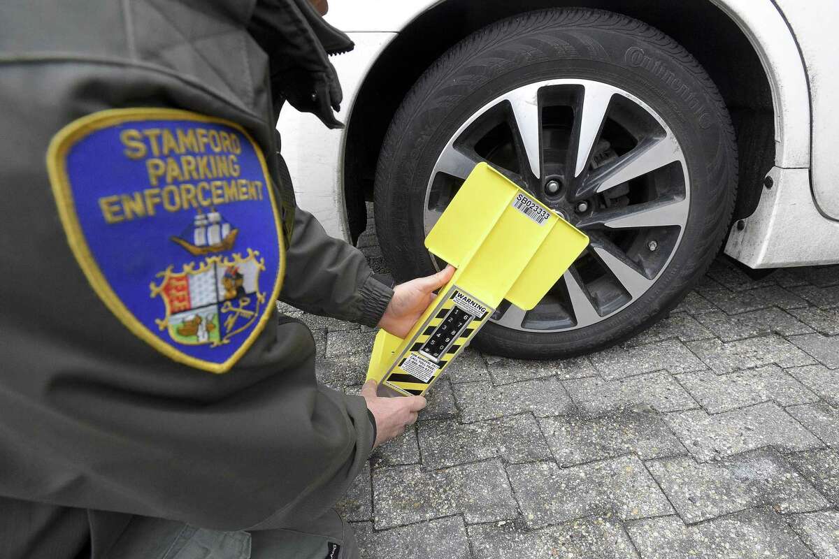 A Stamford Parking Enforcement Officer demonstrates use of a self-releasing electronic boot on Thursday, Feb. 7, 2019 in Stamford, Connecticut.