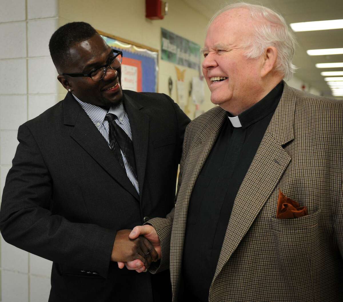 Former Notre Dame of Fairfield basketball and baseball star Tony Barr, left, shakes hands with school president Rev. William Sangiovanni during a visit to his former high school in Fairfield, Conn. on Thursday, May 2, 2013. Barr served over twenty years in prison for drug trafficking.