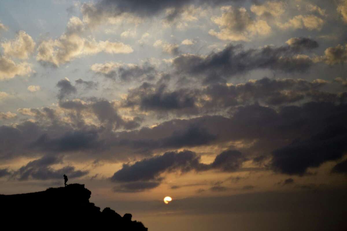A person watches the sunset from a cliff overlooking the Mediterranean sea in Hadera, Israel, Thursday, Feb. 7, 2019.