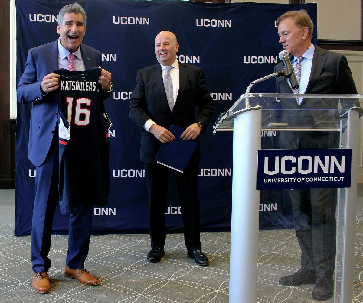 Thomas Katsouleas, left, is presented with a UConn basketball jersey by University of Connecticut Board of Trustees chairman Thomas Kruger, center, and Connecticut Gov. Ned Lamont after being appointed as the University of Connecticut’s 16th president on Tuesday, Feb. 5, 2019 in Storrs, Conn.