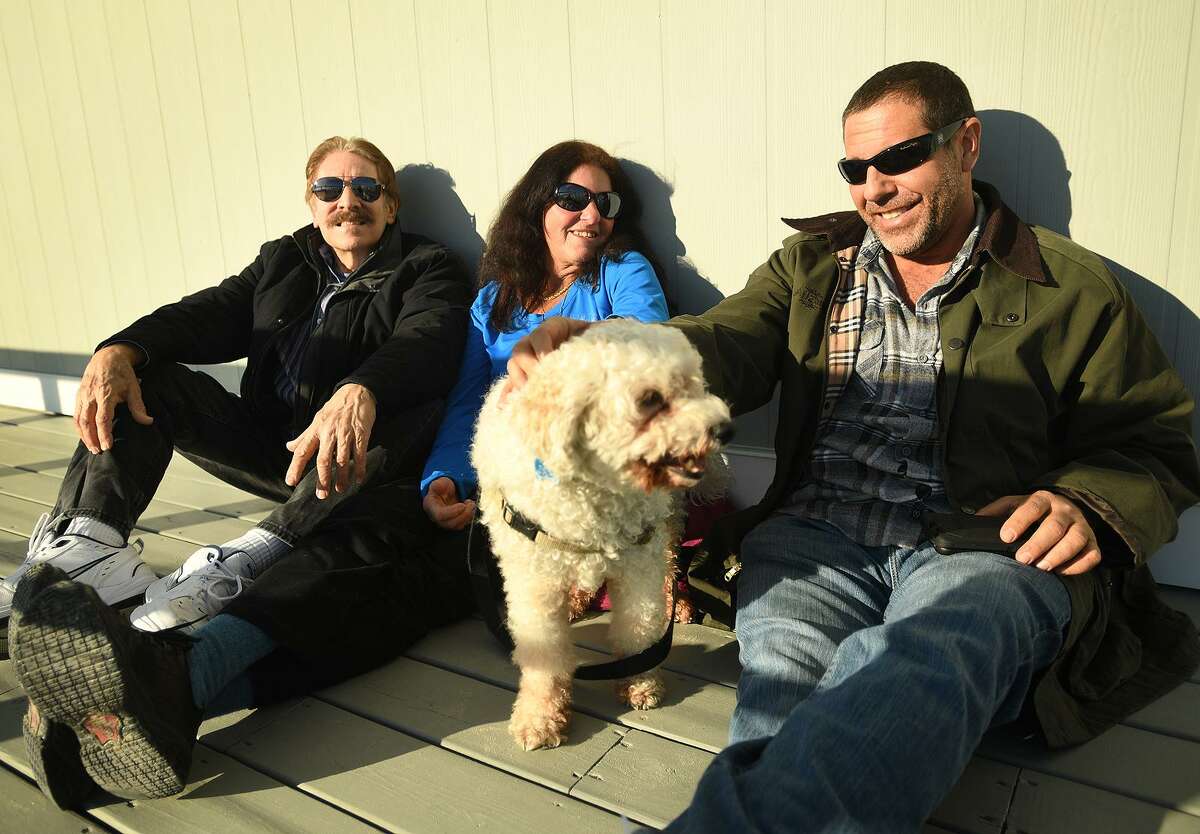 From left, Steve Kaye, Alison Kovachi, Kovachi’s dog Buddy, and Ed Celski, all of Fairfield, enjoy the warmer temperatures at Penfield Beach in Fairfield on Monday.