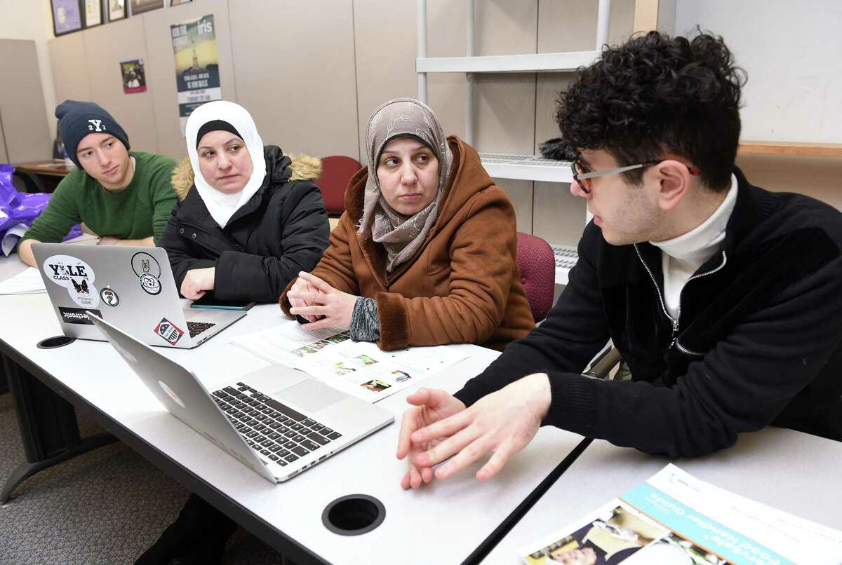 Yale University first-year student Mourad Frishkopf, left, and junior Nour Hussari, right explain the ordering system for the organization Havenly Treats to Syrian refugees Faten Natfaji, center left, and Hala Ghali, center right, at the offices of Integrated Refugee and Immigrant Services in New Haven on Feb. 1.