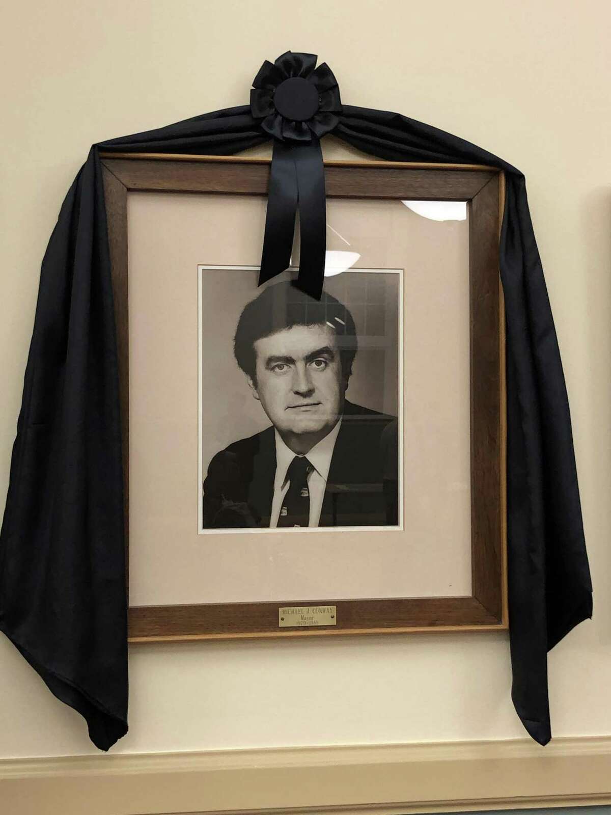 A portrait of former Mayor Michael J. Conway Jr., draped with memorial bunting, is displayed in the City Hall Auditorium.