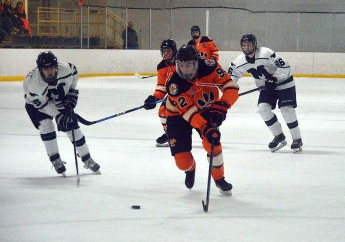 Edwardsville senior Matt Kocarnik, middle, carries the puck during the first period of a Feb. 2 playoff game against Marquette at the Brentwood Ice Rink.