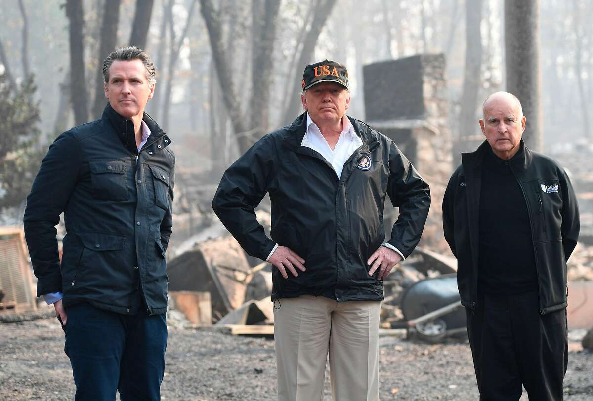 US President Donald Trump (C) looks on with Governor of California Jerry Brown (R) and Lieutenant Governor of California, Gavin Newsom, as they view damage from wildfires in Paradise, California on November 17, 2018. Newsom recently announced his intention to withdraw most of California's National Guard troops from the border, saying the state needs them to prepare for wildfires and to fight drug trafficking. (Photo credit should read SAUL LOEB/AFP/Getty Images)