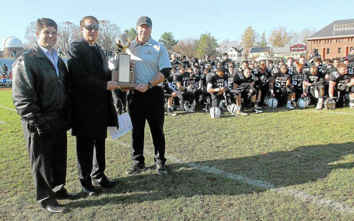 Tom Serra, middle, was a fixture at Middletown-Xavier Thanksigivng football games presenting the championship trophy, sponsored by the Middletown Hall of Fame. He is seen here presenting Xaver’s Sean Marinan after the 14th annual game, along with Mayor Dan Drew.