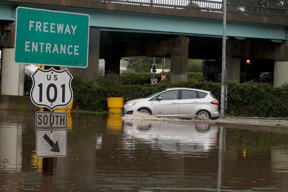 A car navigates its way through a flooded area to a freeway onramp along Alemany Boulevard on Wednesday, February 13, 2019 in San Francisco, Calif.