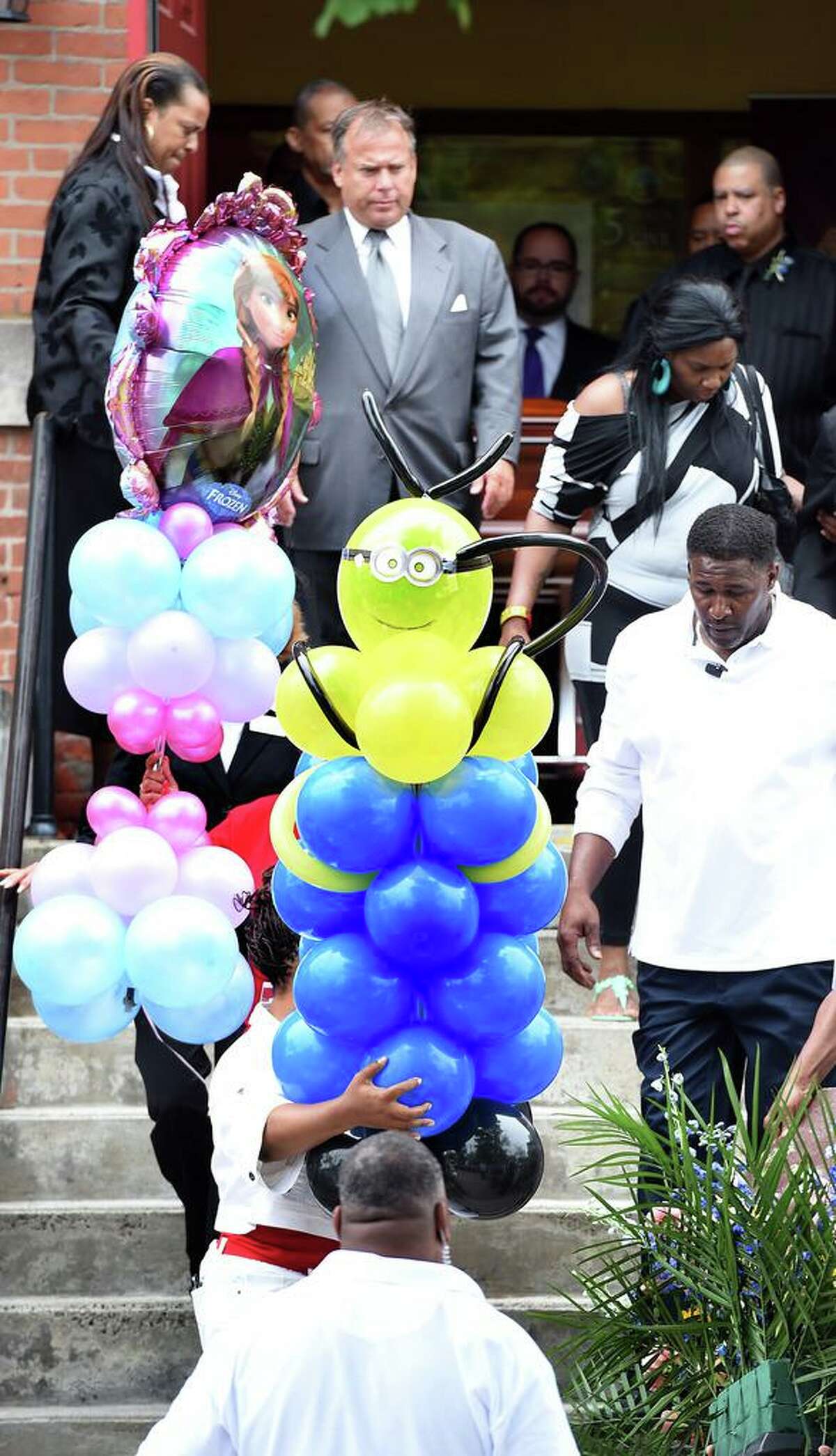 Balloon bouquets are carried for Aleisha Moore (left), 6, and Daaron Moore, 7, of East Haven, Connecticut, out of Varick Memorial A.M.E. Zion Church in New Haven, Connecticut, on Tuesday, June 16, 2015. Aleisha's balloons (left) were inspired by the movie, Frozen, and Daaron's have a Minions theme. The children's mother, LeRoya Moore, is detained on murder charges and wasn't allowed to attend the funeral.