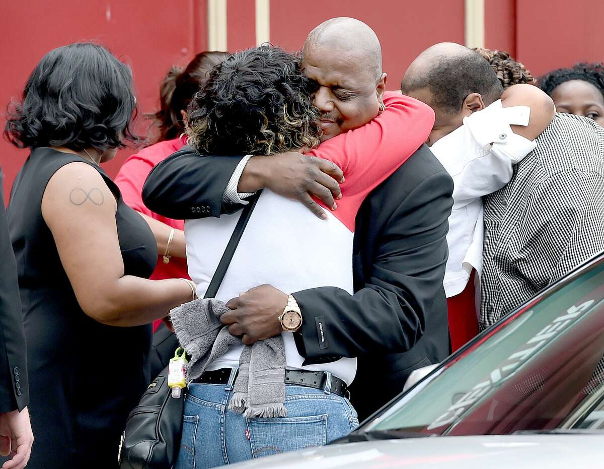 Michael Moore, center, father of deceased children Aleisha, 6, and Daaron, 7, is hugged outside of Varick Memorial A.M.E. Zion Church before funeral services for the children in New Haven June 16, 2015.