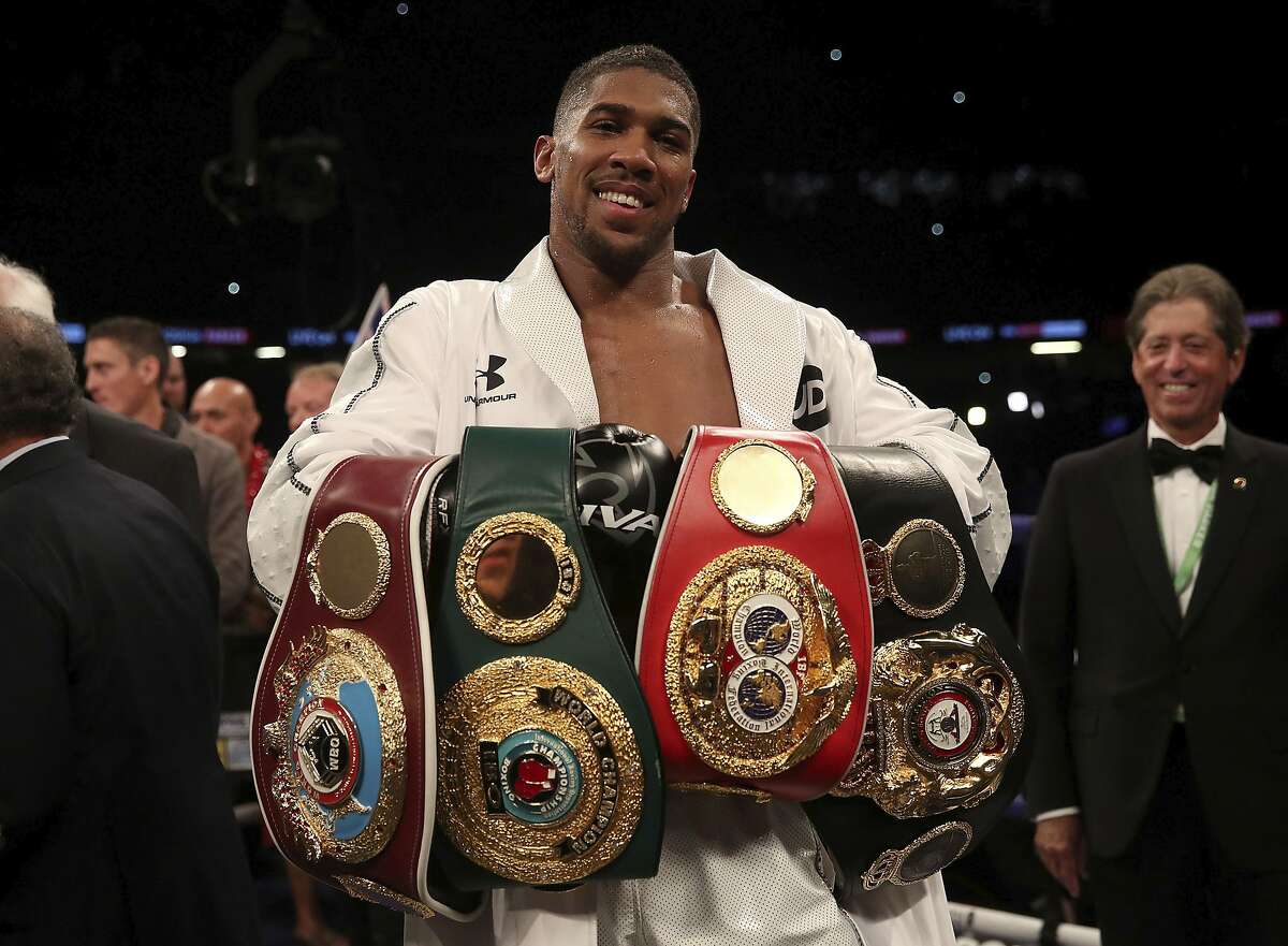 Anthony Joshua celebrates with his belts after victory over Joseph Parker to become the WBA, IBF and WBO heavyweight champion at the Principality Stadium in Cardiff, Wales, Saturday March 31, 2018. (Nick Potts/PA via AP)