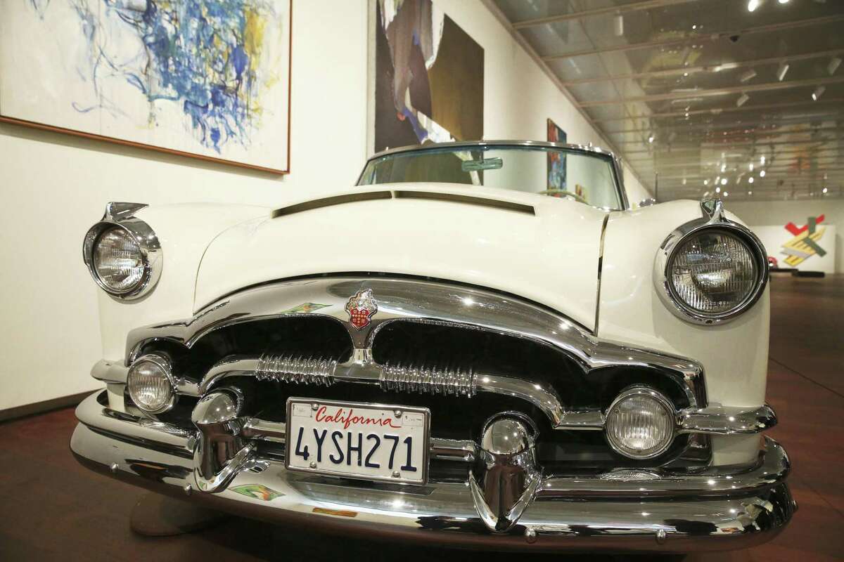 A 1954 Packard Caribbean with California plates rests under artwork in the McNay Art Museum’s "American Dreams: Classic Cars and Postwar Paintings.”