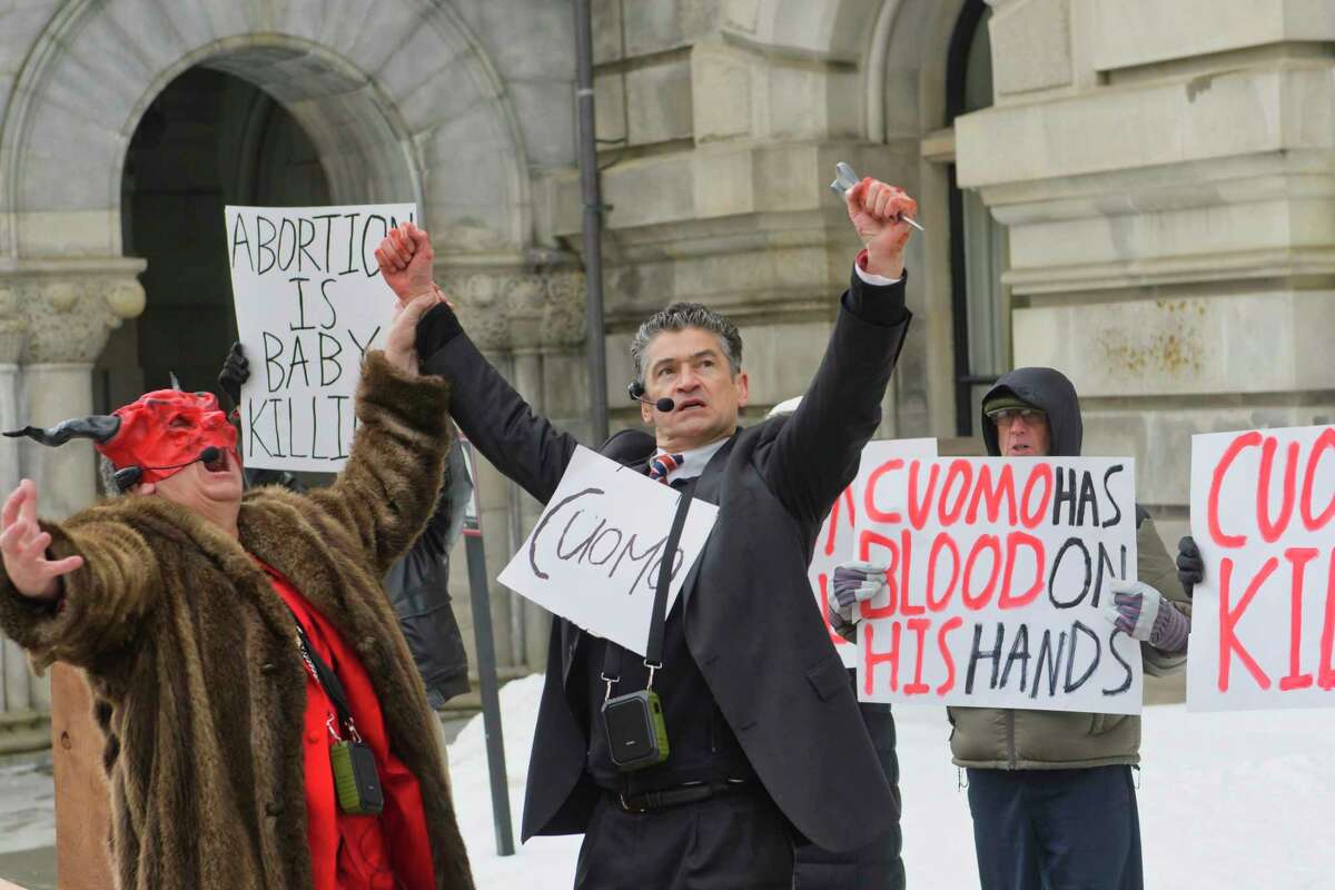 Pro-life leader, Randall Terry, left, dressed as Satan, raises the hand of Gary Boisclair, who plays the part of Governor Andrew Cuomo during a street theatre performance outside the Capitol on Thursday, Feb. 14, 2019, in Albany, N.Y. The stop in Albany was part of Terry's ?Christ, Cuomo, and Satan Tour to call attention to what he says is New York State's aggressive promotion of late term abortion. (Paul Buckowski/Times Union)