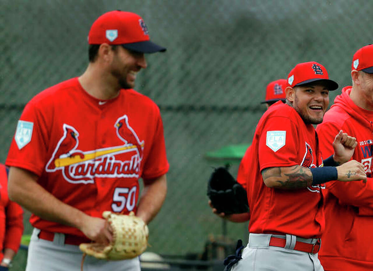 St. Louis Cardinals catcher Yadier Molina, right, laughs after receiving a kiss on the cheek from teammate Adam Wainwright, left, as Wainwright walked past during spring training baseball practice Wednesday, Feb. 13, 2019, in Jupiter, Fla.