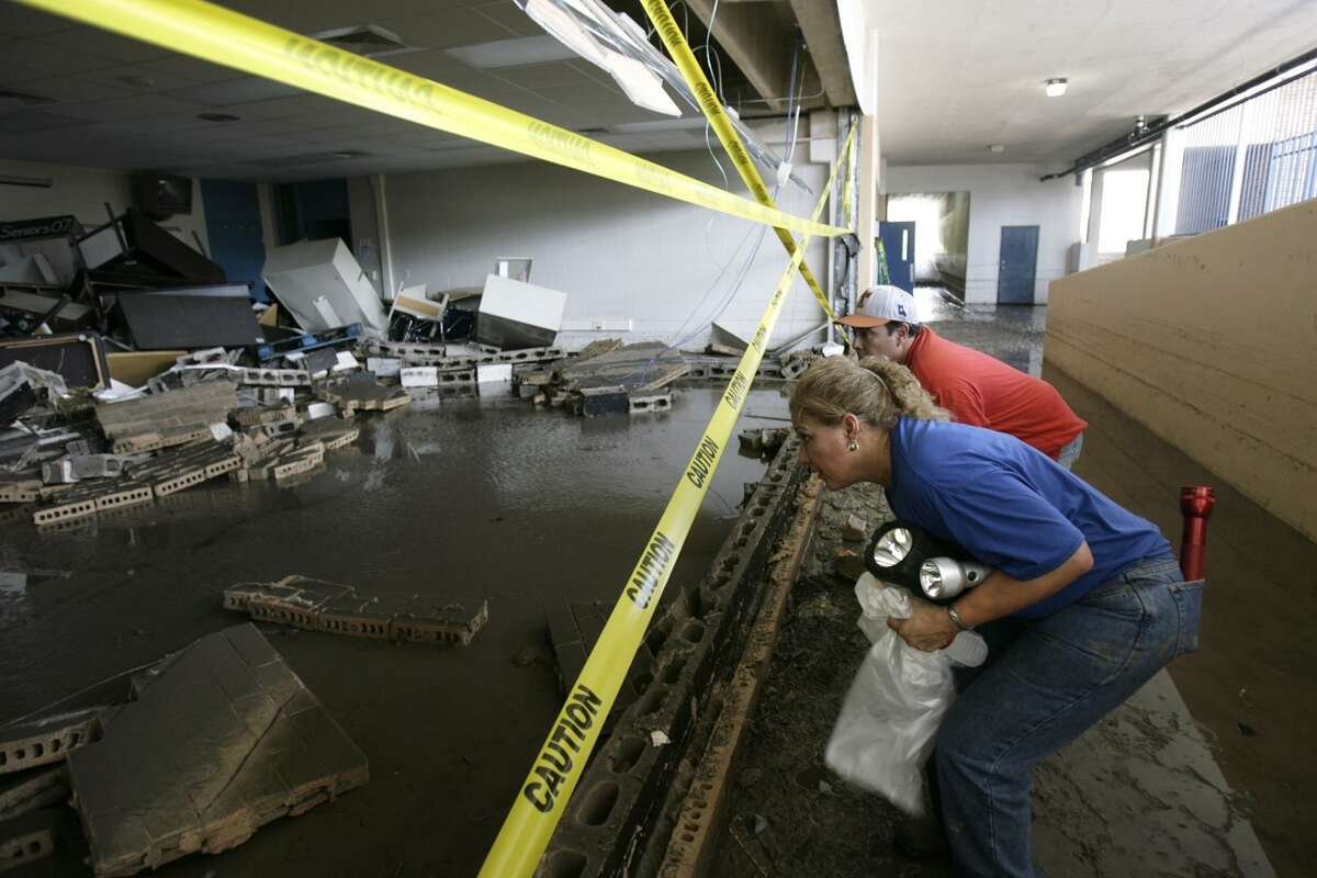 Dyanne Martinez-Munoz, girls athletic coordinator and teacher, front, and Roland Hernandez, teacher and coach, look at flood damage at West Campus High School in August 2007. The school has been closed ever since, but a new majority on the South San Antonio ISD board is demanding that it reopen in August.