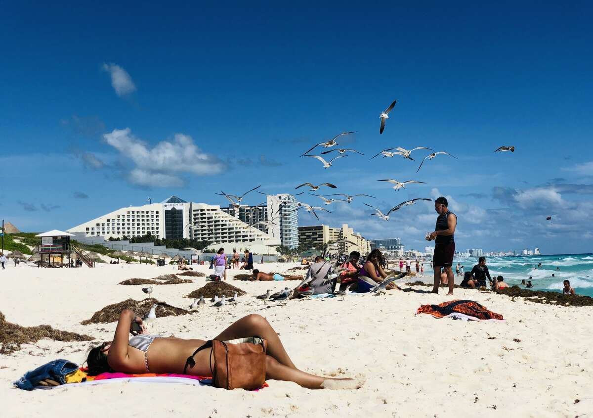 A flock of seagulls flies over beachgoers in the seaside tourist resort of Cancun, in Quintana Roo state, Mexico on February 16, 2019. - Playa del Carmen and Cancun are the top tourist destinations in Mexico, famous for their turquoise waters and white-sand Caribbean beaches. (Photo by Daniel SLIM / AFP) (Photo credit should read DANIEL SLIM/AFP/Getty Images)