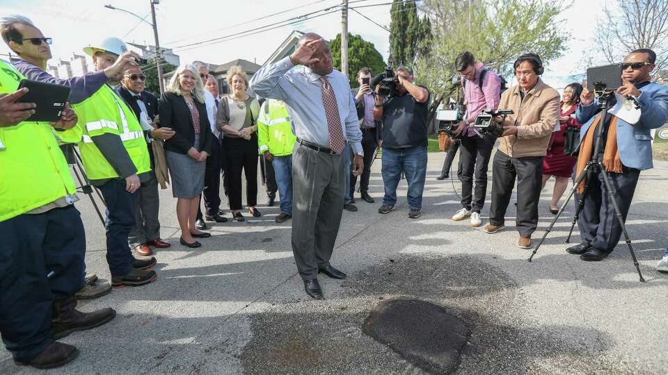 Mayor Sylvester Turner jokes about how hard he worked to fill in a pothole after a Houston Public Works team filled it in at Dart and Holly streets on Monday.