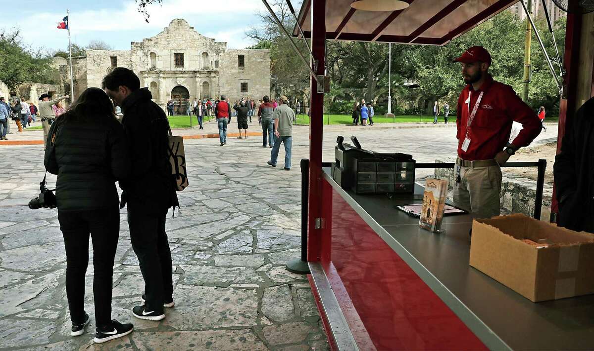 Tourists look through a brochure they picked up at the new Alamo “Welcome Center,” Feb. 18. A reader wants the city to recognize those who may be buried beneath Alamo grounds.