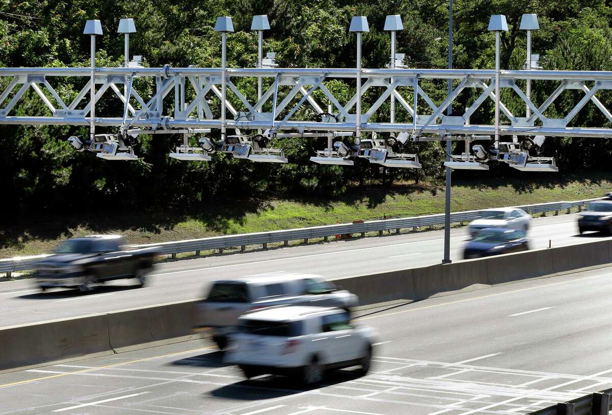 In a file photo, cars pass under toll sensor gantries hanging over the Massachusetts Turnpike.