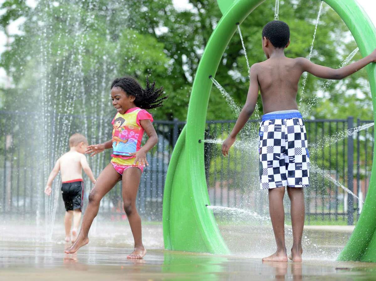 Five-year-old Desiree Hutchins, of Danbury, runs through a spray of water Wednesday, July 8, 2015, at the Splash Pad at Rogers Park in Danbury as her brother Ethan, right, looks on.