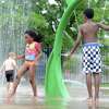 Five-year-old Desiree Hutchins, of Danbury, runs through a spray of water Wednesday, July 8, 2015, at the Splash Pad at Rogers Park in Danbury as her brother Ethan, right, looks on.