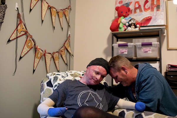 Zachary Sutterfield and his father, Karl Sutterfield, lean on each other in their Fisher House apartment at Joint Base San Antonio-Fort Sam Houston.