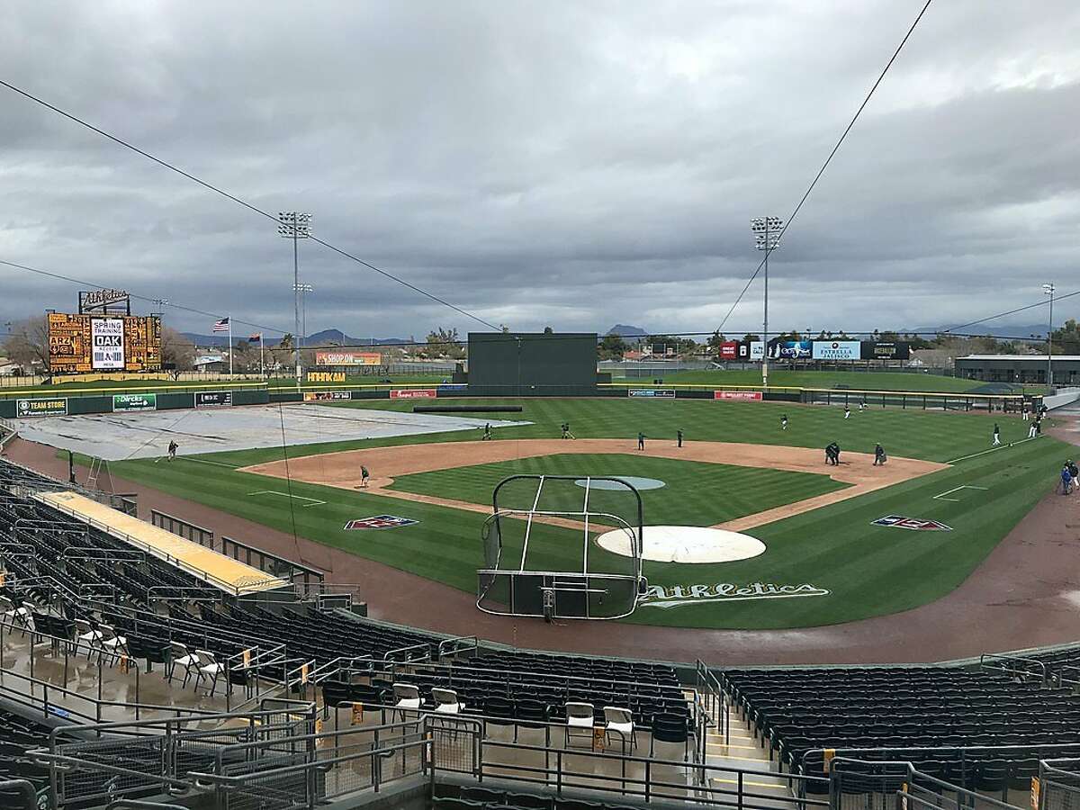 Beneath dark skies, the grounds crew prepares the field for the A's Cactus League opener at Hohokam Stadium on Thursday.