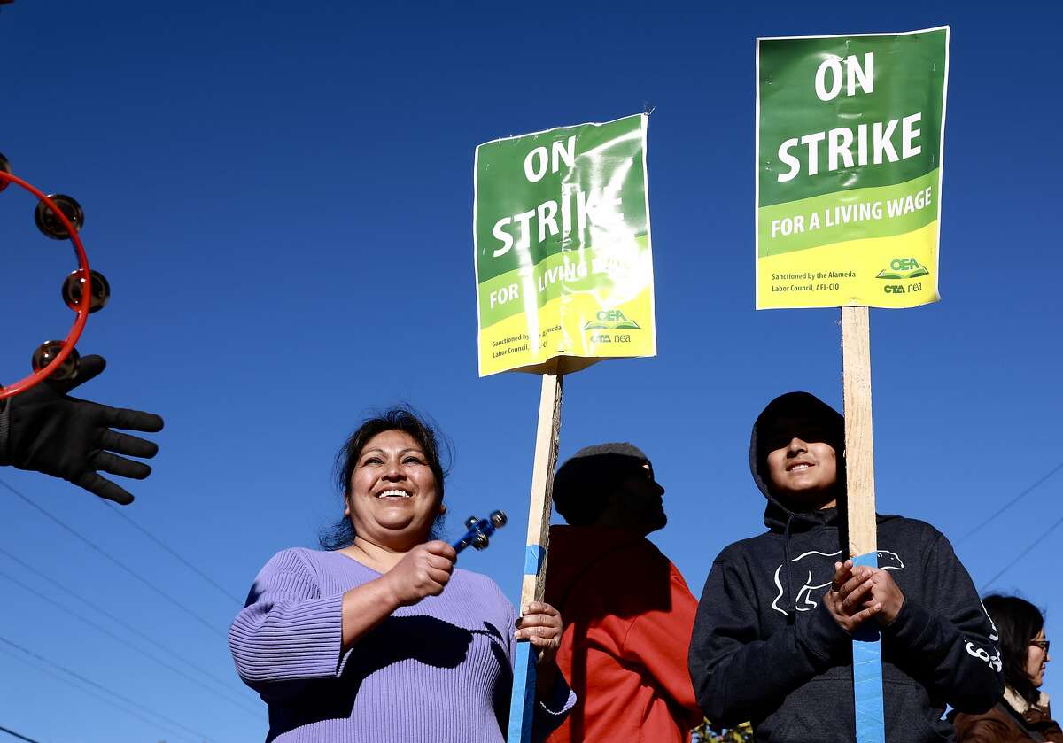 Isabel Burgos and her son, Adrian Burgos, 12, a 7th grade student at Melrose Leadership Academy, participate in the Oakland Teachers Strike outside the school in Oakland, Calif., on Thursday, February 21, 2019.