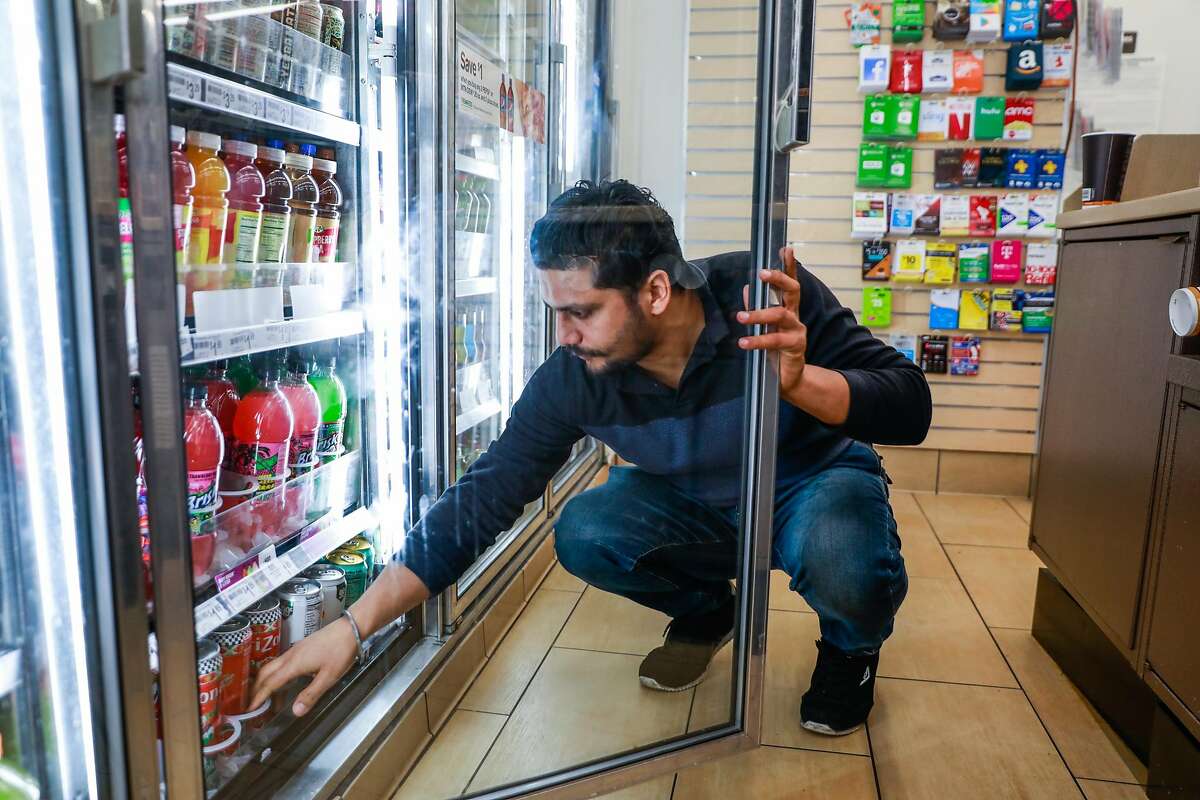 7-11 employee Rajan Bhatti checks if he needs to re-stock the soda refrigerators at the 7-11 on Mission Street in San Francisco, California, on Monday, Feb. 18, 2019.