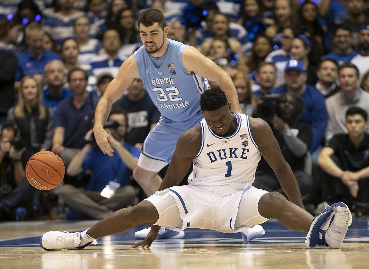 Duke's Zion Williamson (1) falls to the court under North Carolina's Luke Maye (32), injuring himself and damaging his shoe during the opening moments of the game in the first half on Wednesday, Feb. 20, 2019, at Cameron Indoor Stadium in Durham, N.C. (Robert Willett/Raleigh News & Observer/TNS)