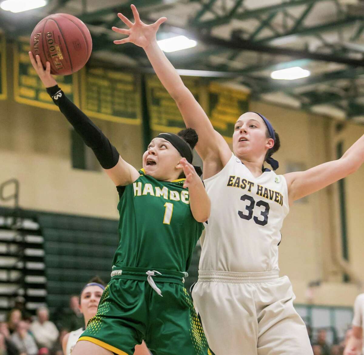 Hamden’s Asya Brandon goes in for a layup past East Haven defender Taylor Salato during the SCC championship game on Thursday.