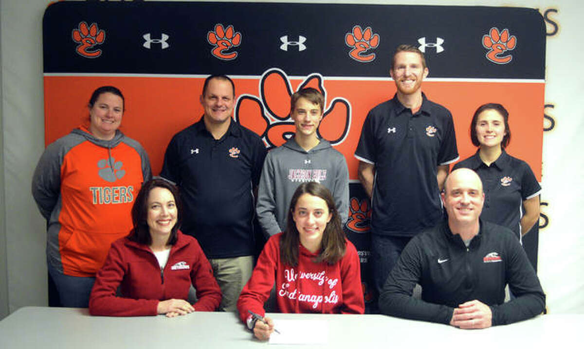 Edwardsville senior Maddie Miller, seated center, is joined by her family and EHS coaches as she signs to compete in cross country and track and field at the University of Indianapolis.