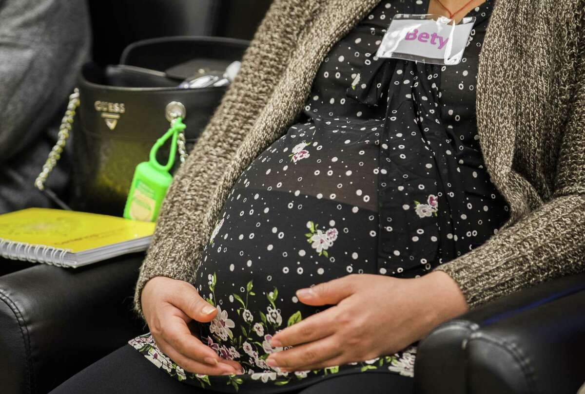 A woman rests her hands on her baby bump at a prenatal care group session at El Centro de Corazón on Tuesday, Feb. 12, 2019, in Houston. The state’s family planning programs provide critical services like birth control, STD screenings and mammograms.
