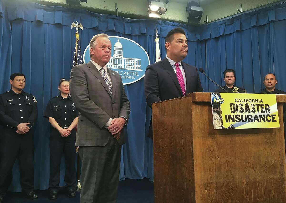 Democratic state Sen. Bill Dodd of Napa, left, and Insurance Commissioner Ricardo Lara, right, at the podium, speak at a news conference as Sacramento City Fire Department firefighters stand behind in the state Capitol in Sacramento, Calif., Thursday, Feb. 14, 2019. The two statewide officials want California to take out insurance to help cover taxpayers' costs in bad wildfire seasons. California has experienced 11 of the top 20 most destructive fires in its history since 2007. (AP Photo/Don Thompson)
