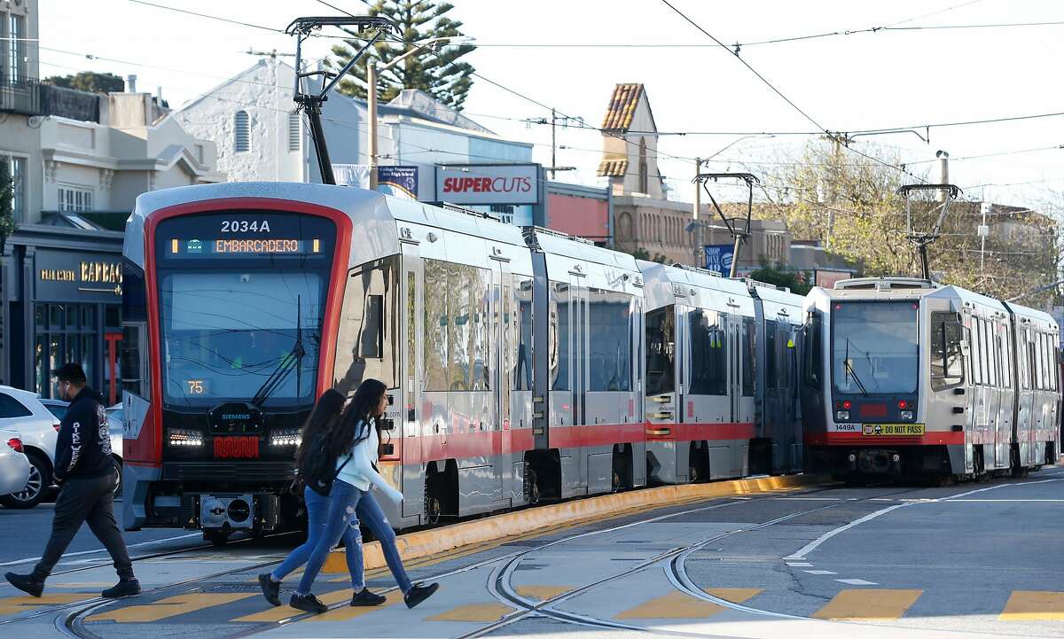 Pedestrians cross in front of trains outside of the West Portal Muni station in San Francisco on Feb. 22, 2019. Board directors for the Municipal Transportation Agency have picked Tom Maguire, a five-year staffer who began his career in New York, to be the new interim transportation chief.