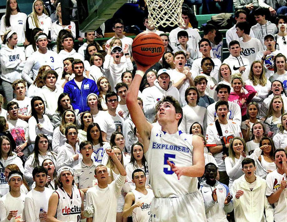 Marquette Catholic’s student section dressed in white watches the Explorers’ Chris Hartrich get to the basket for a layup on a backdoor cut out of the Explorers offense midway through the fourth quarter of the Southwestern Class 2A Regional title game in Piasa. Photo: Greg Shashack | The Telegraph