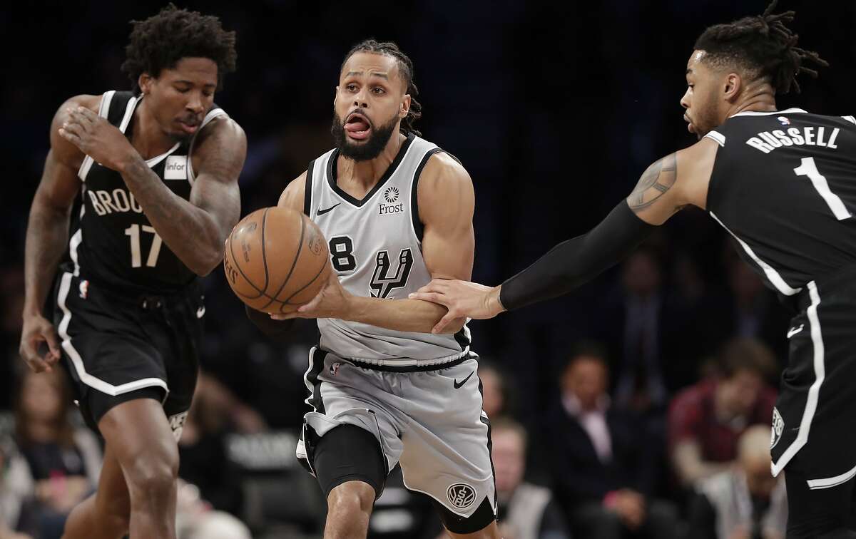 Brooklyn Nets guard D'Angelo Russell (1) grabs the arm of San Antonio Spurs guard Patty Mills (8) during the first half of an NBA basketball game, Monday, Feb. 25, 2019, in New York. (AP Photo/Kathy Willens)