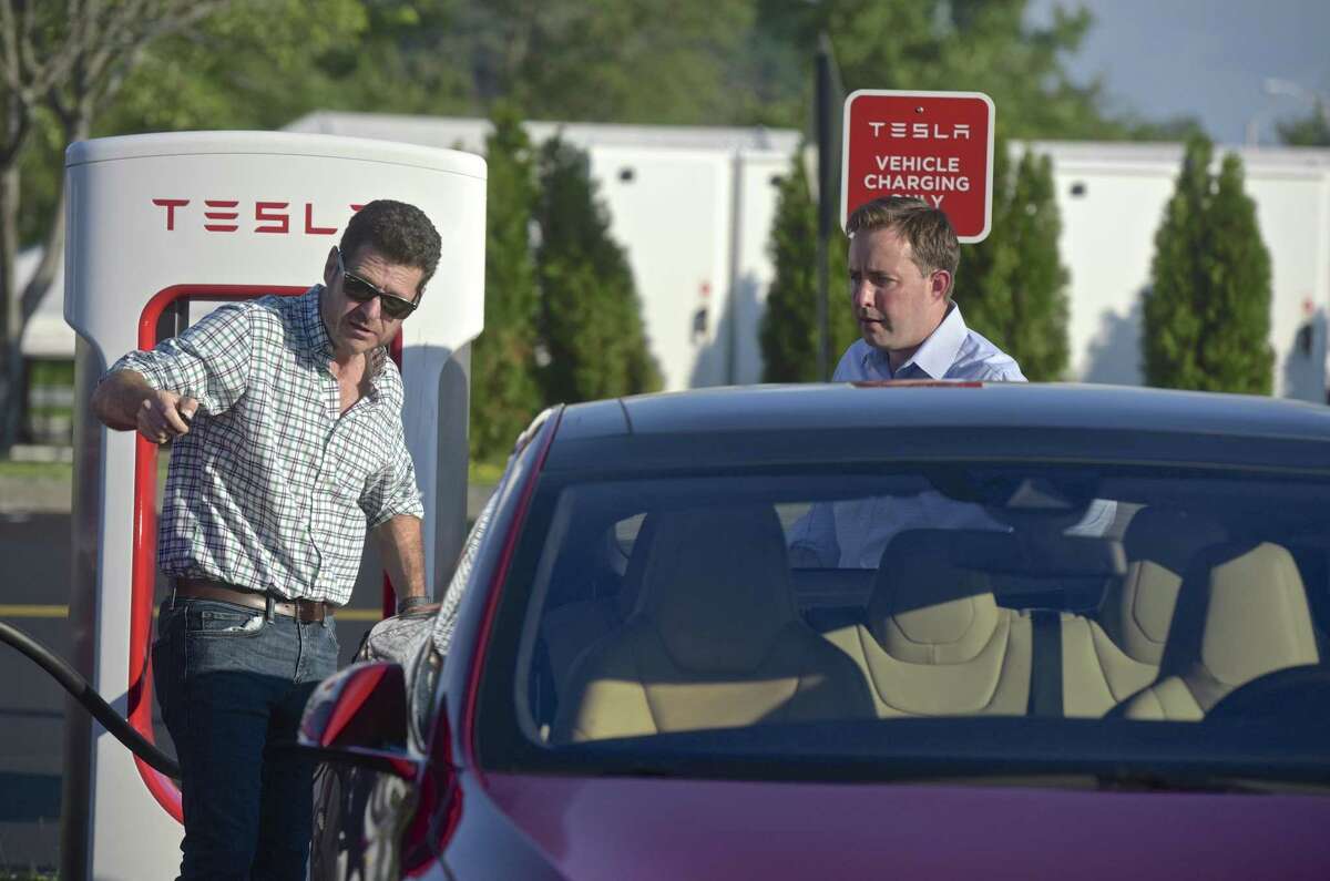 Phil Levieff, of Fairfield, left, demonstrates the ability of his Tesla model S to park itself to Adam Wood, of Rocky Hill, at the Tesla Supercharger Station at the Danbury Fair mall.