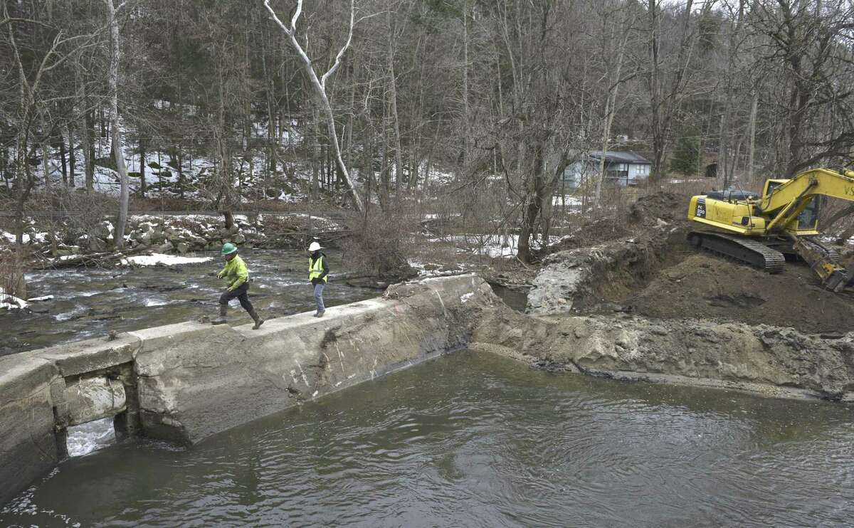 Excavator operator Jarrod Martellacci, left, and Project coordinator Becky Cohn, from SumCo Eco Contracting, walk across the Old Papermill Dam on the East Aspetuck River. The Dam belongs to the Ousatonic Fish & Game Protection Association and its removal is being overseen by the Nature Conservancy. Friday, February 22, 2019, in New Milford, Conn.