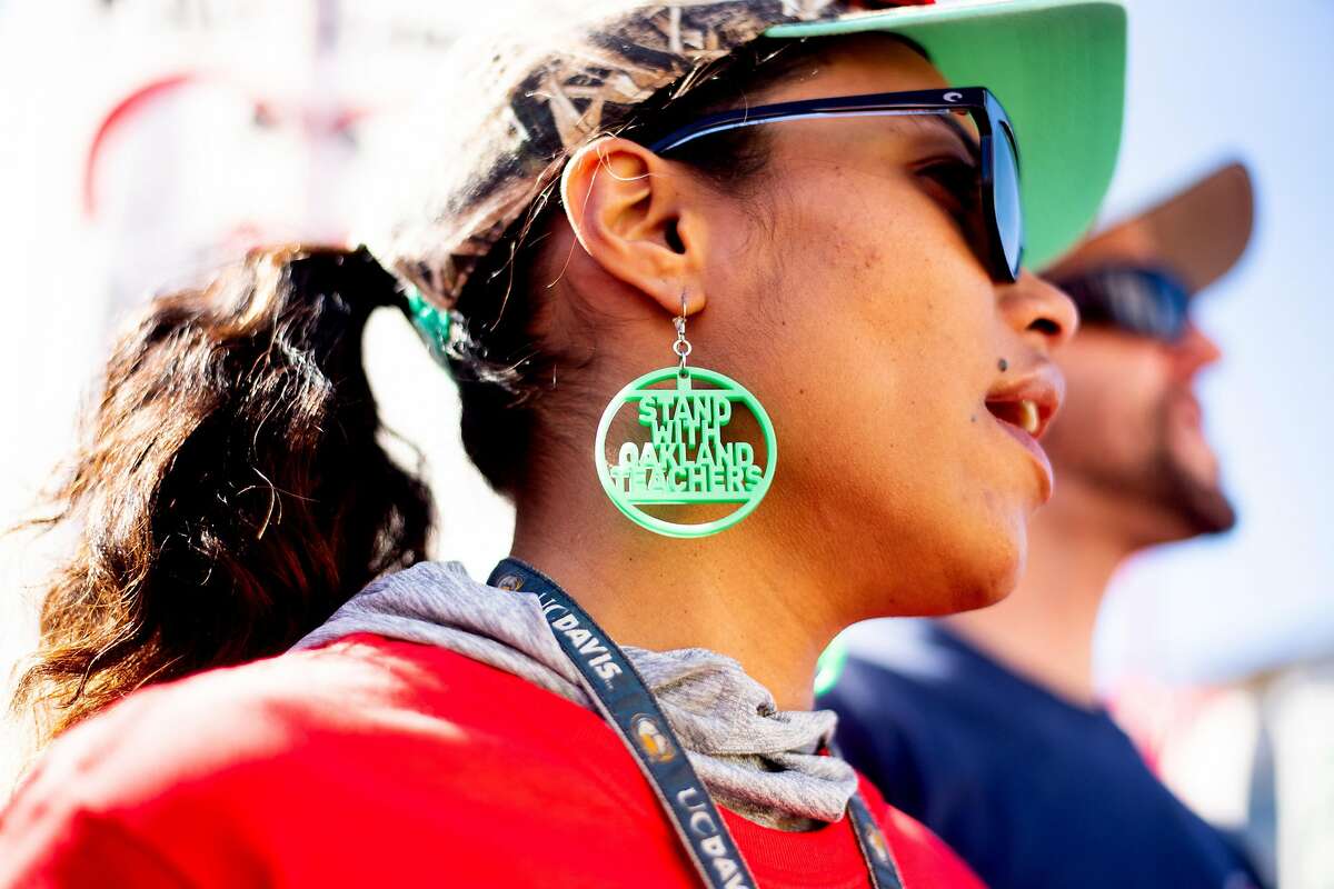 India Leeward, a teacher at Oakland's New Highland Academy, wears protest earrings while rallying in DeFremery Park on Friday, Feb. 22, 2019, in Oakland, Calif. Several hundred people showed up for the protest during day two of the Oakland teacher strike.
