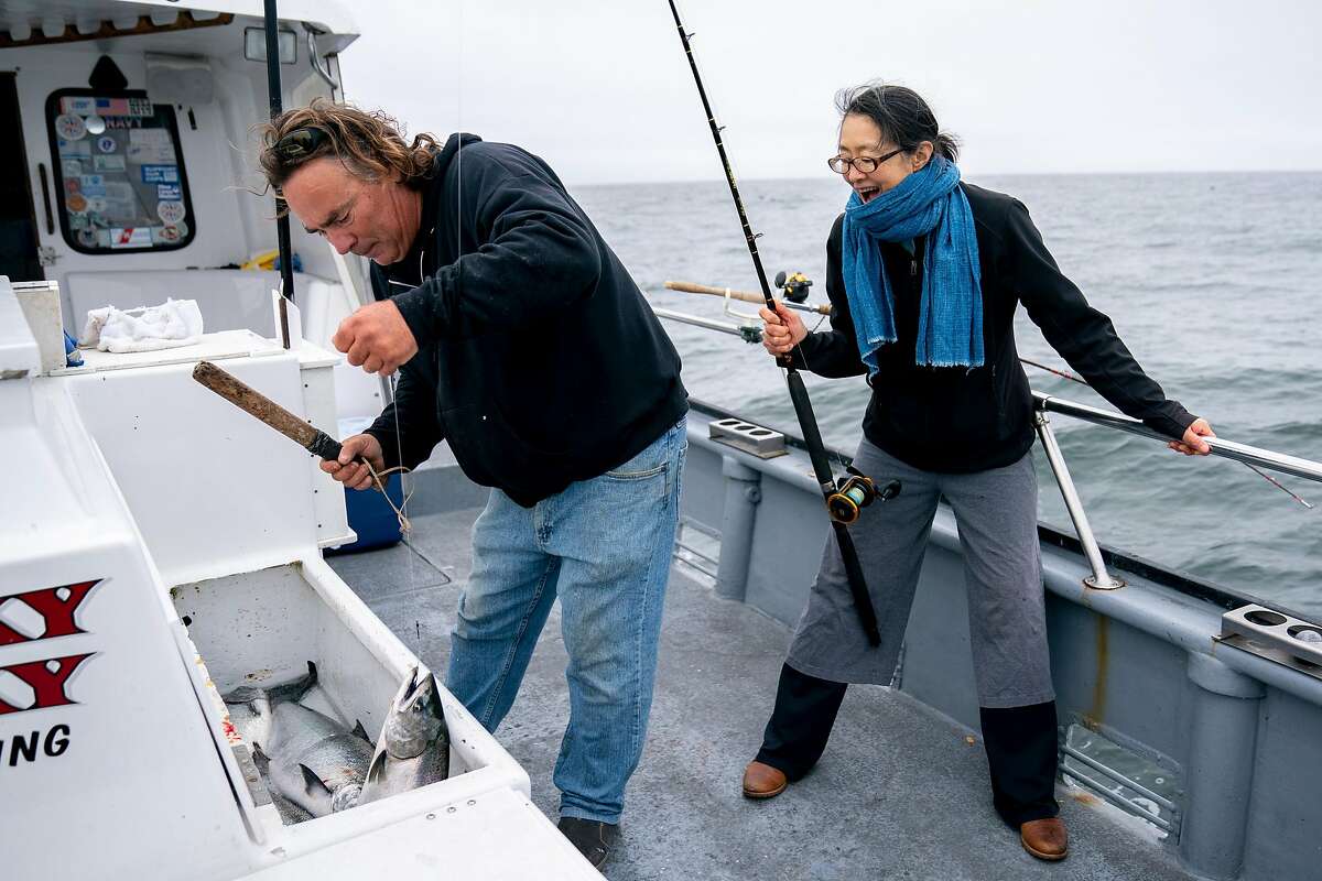 From left: John Dresser using a priest to kill the Chinook Salmon after Mariko Grady reeled the fish into the Whacky Jacky fishing boat on Tuesday, Sept. 18, 2018, off the coast of San Francisco, Calif.