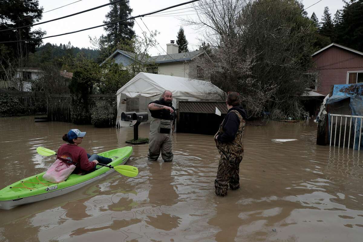 Erin Cardiff, left, stops to talk to her neighbors, Josh Hogg, center, and Teake Bartling, right, near River Road in Forestville, Calif., on Thursday, February 28, 2019. The area along the Russian River sustained heavy flooding after an atmospheric river dumped almost 20 inches of rain in two days.