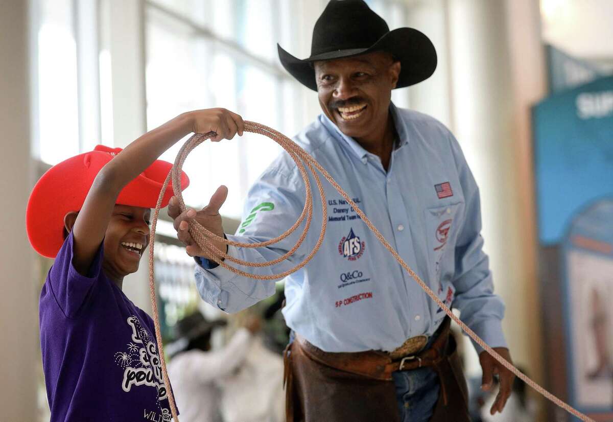 Larry Callies, right, helps teach Carson Greigg, 8, how to throw a lasso at the Houston Livestock Show and Rodeo Friday, March 1, 2019, in Houston.