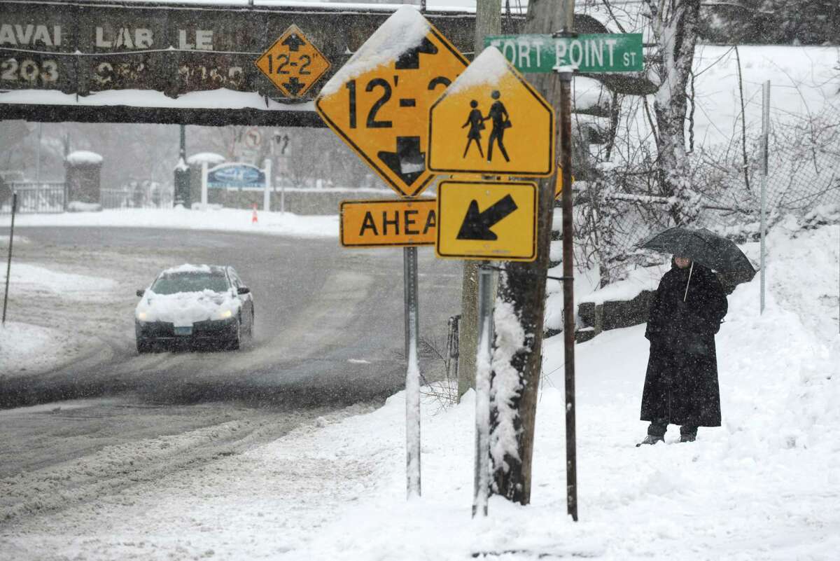 A pedestrian waits along East Ave. during the snow storm Saturday March 2, 2019, in Norwalk, Conn.