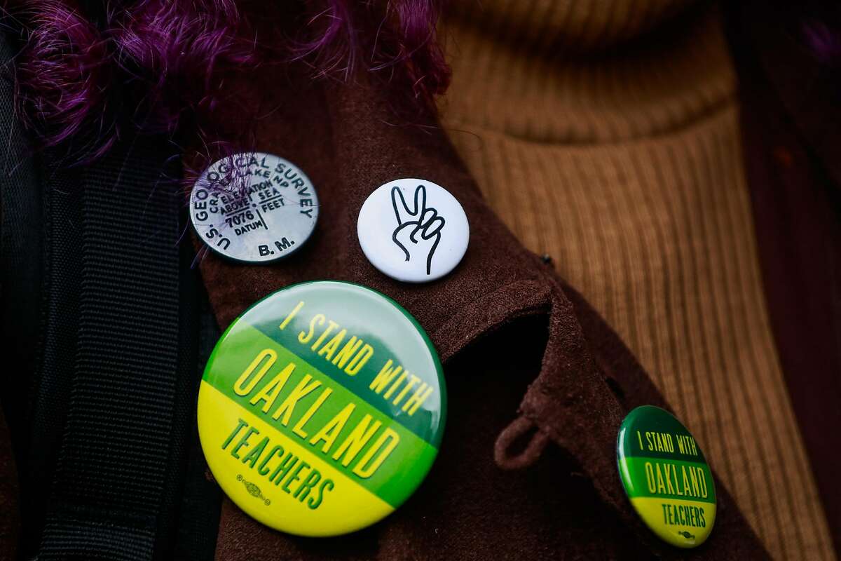 A teacher shows off her pins as she lines up with other teachers to vote on whether or not to ratify a tentative contract that the Oakland Education Association and Oakland Unified School District proposed in Oakland, California, on Sunday, March 3, 2019.