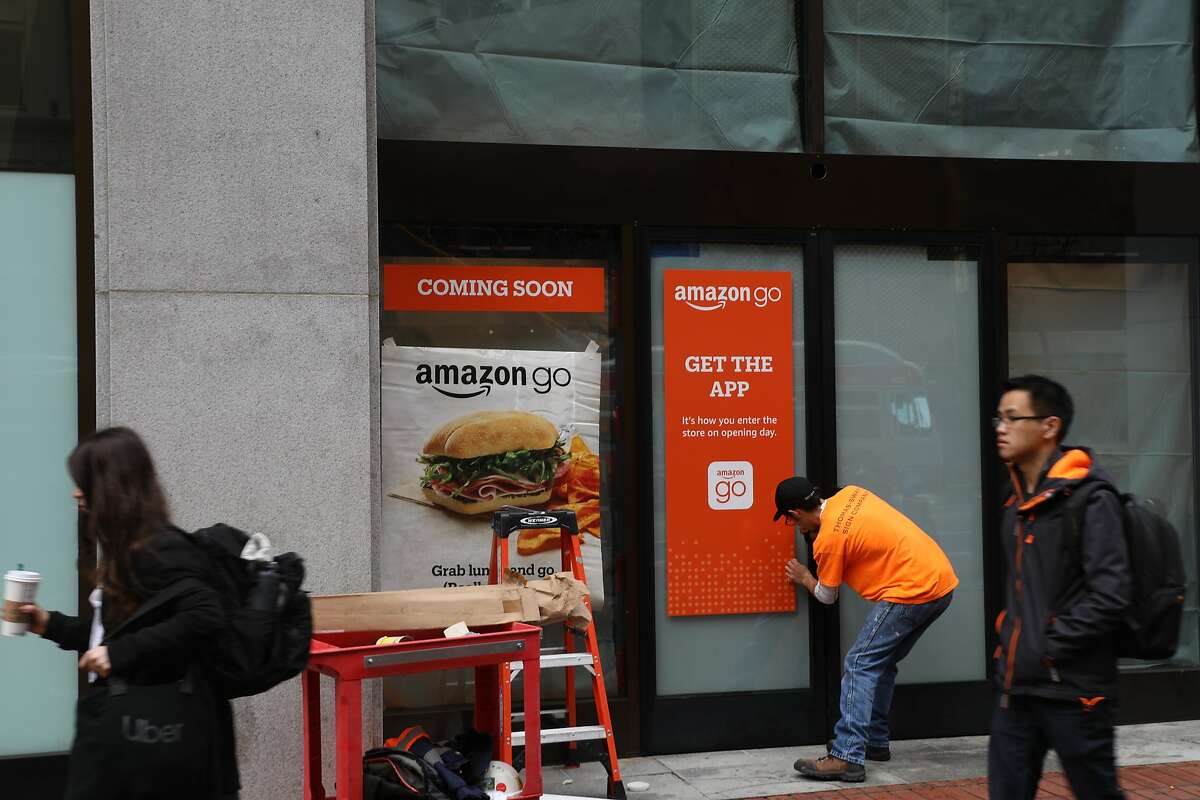 一名工人在位于市场街575号的未来无收银商店安装亚马逊Go标志，这是旧金山的第三家。