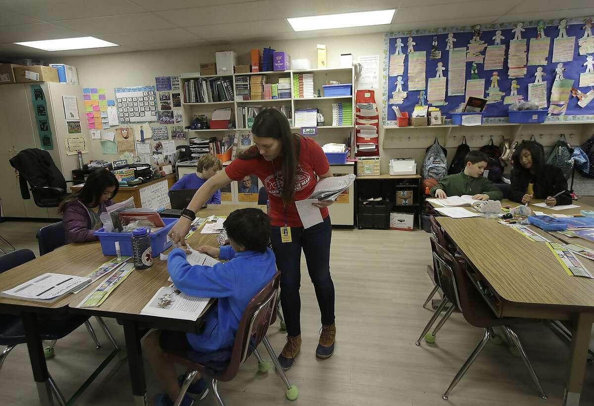 Chabot Elementary School fourth grade teacher Laura Shield talks with a student in her class in Oakland, Calif., Monday, March 4, 2019. Thousands of Oakland teachers are back in classrooms after union members voted to approve a contract deal. (AP Photo/Jeff Chiu)