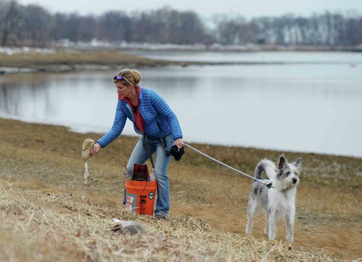 Greenwich's Christine Sweeney finds a plastic bottle while collecting trash with her dog, Blue, at the Greenwich Point Park Cleanup in Old Greenwich, Conn. Sunday, March 3, 2019. Skip the Straw Greenwich, Surfrider Foundation CT and BYOGreenwich helped organize the event and bring together hundreds of volunteers to comb through Tod's Point in search of trash. Volunteers collected garbage and left it at transfer sites around the park where it was picked up at the end of the two hours of collection to be weighed and sorted.